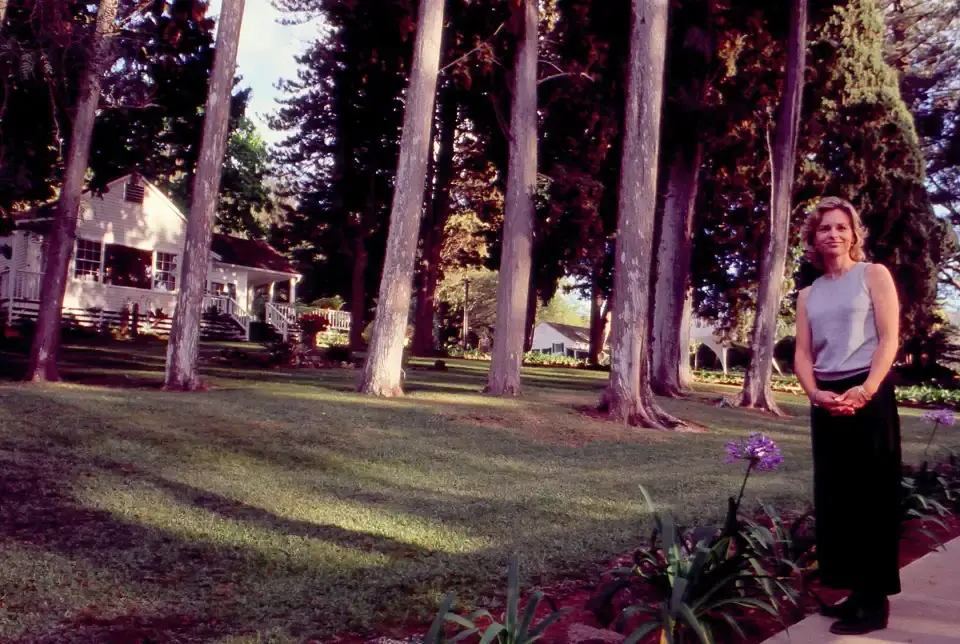 Woman standing on the lawn among tall trees outside the King's Cottage