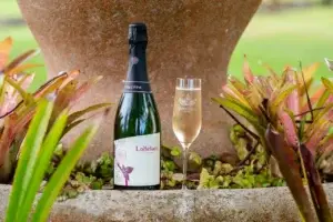 Bottle and flute of Lokelani sparkling rosé in the garden