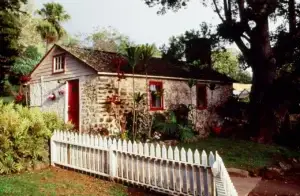 Historic photo of the King's Cottage stone building with a white picket fence