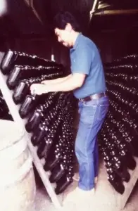 Historic photo of a winemaker riddling sparkling wine bottles