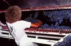 Historic photo of a worker sorting red grapes at the crusher