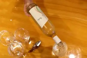 Pouring Kula white wine into glasses on a wooden table