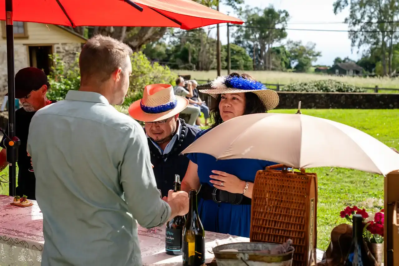 Wine club members mingling under red umbrellas at a MauiWine event