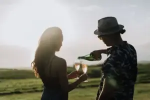 Couple pouring Lokelani sparkling rosé at sunset