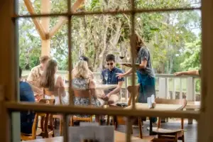 Guests enjoying wine on the tasting room porch seen through the window