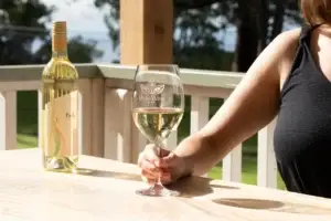 Guest holding a glass of white wine on the tasting room porch