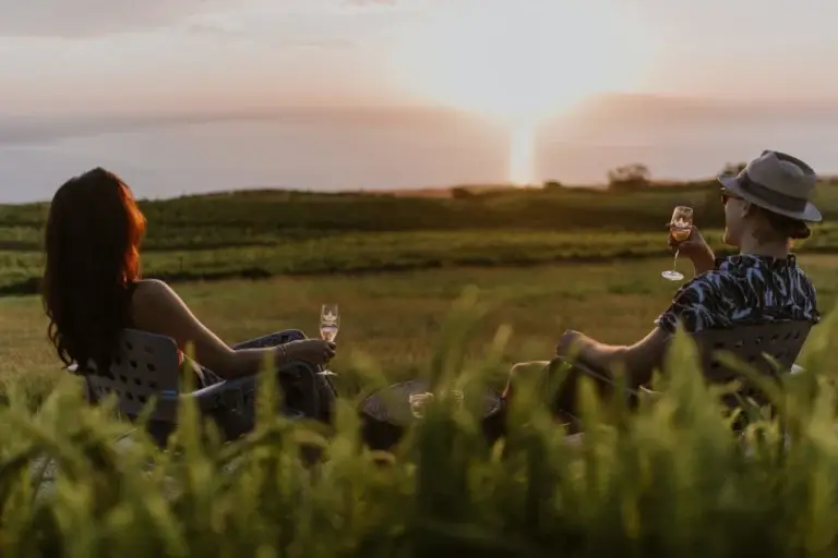 Guests enjoying wine on the lawn at sunset with Maui views