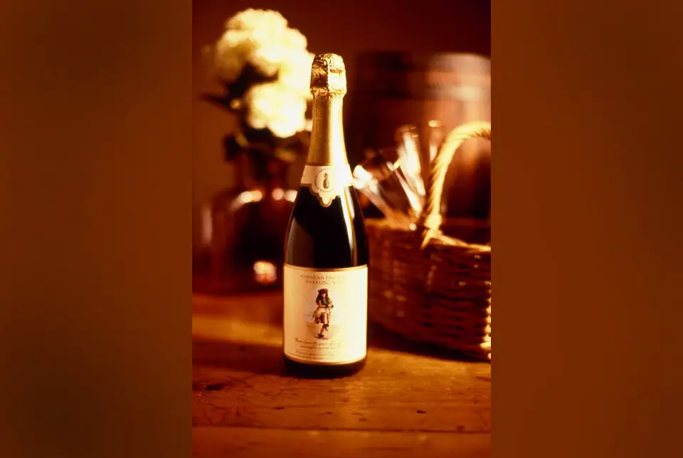 Bottle of MauiWine sparkling wine beside a wooden crate