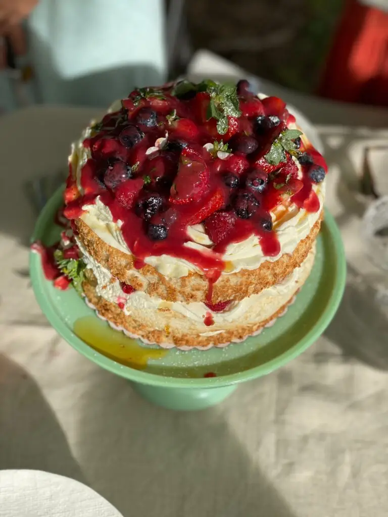 Cake topped with fresh berries and Lehua mixed berry sauce on a green cake stand